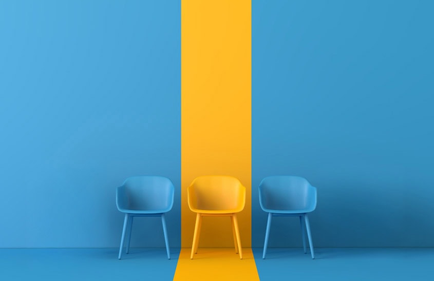 Three chairs against a blue background with a yellow strip and yellow chair in the middle with blue chairs on either side.